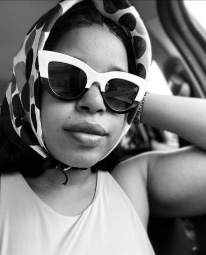 Black girl wearing Black and white sunglasses and polka dot head scarf